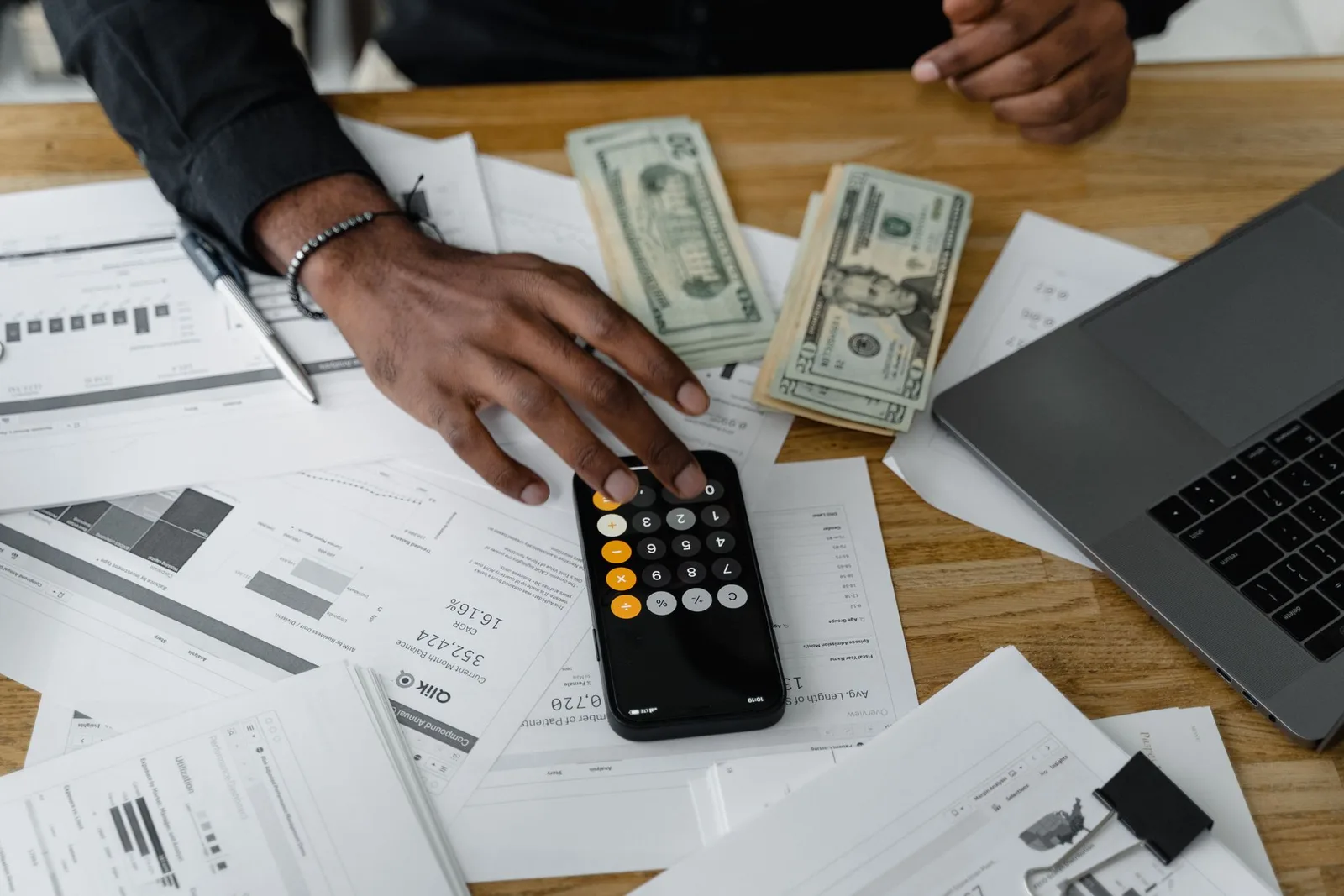 Cash flow planning workspace with a laptop, calculator, banknotes and financial documents